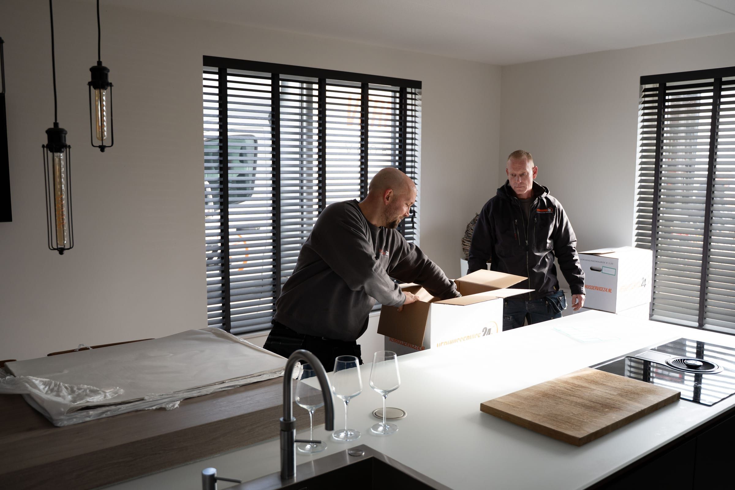 Twee verhuizers pakken samen de keuken in verhuisdozen