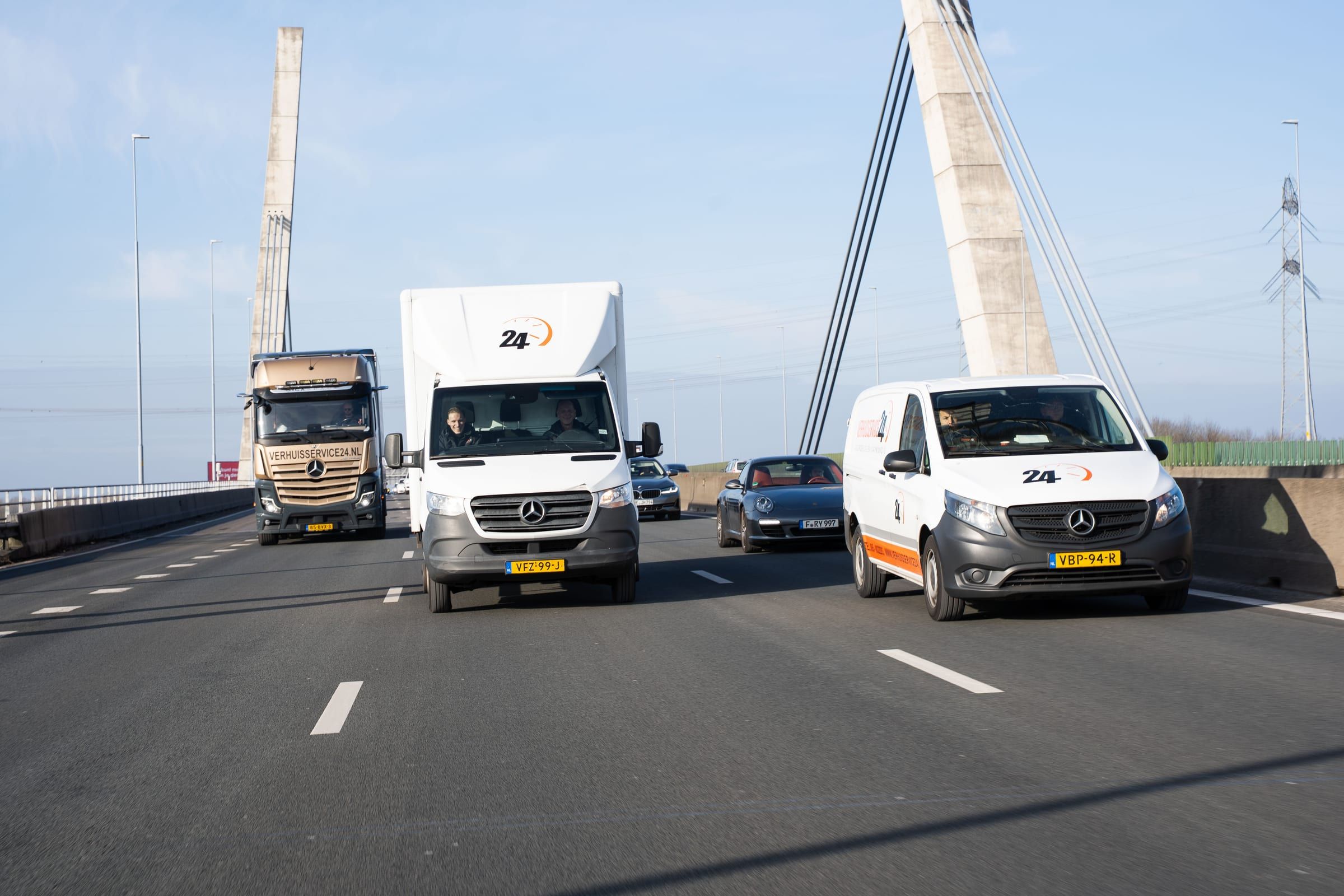 Vrachtwagen, bakwagen en bestelbus van Verhuisservice24 rijden samen over de snelweg