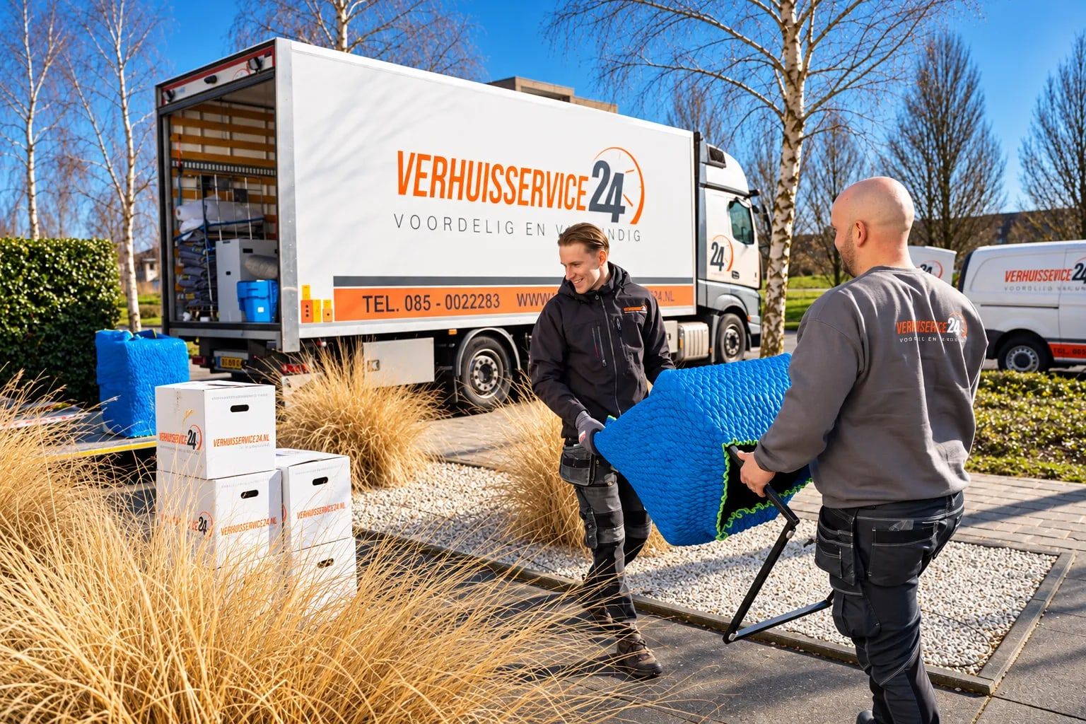 Twee verhuizers van Verhuisservice24 dragen een ingepakt meubel naar de verhuiswagen