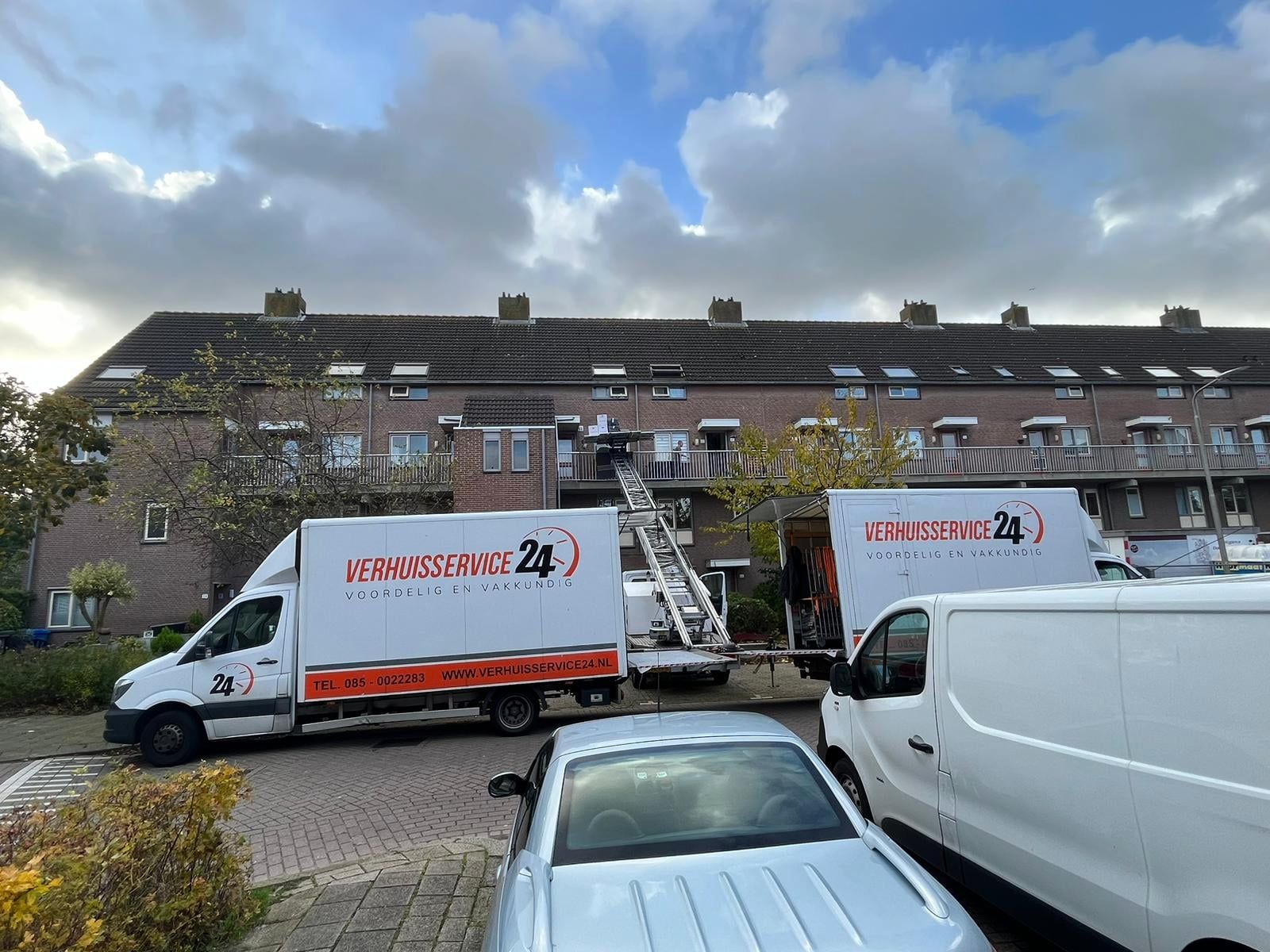 Twee verhuiswagens van Verhuisservice24 met de verhuislift tussen de woningen